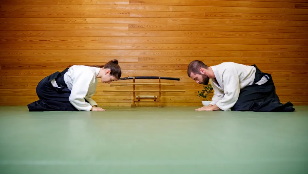 İki aikidoka kılıç sehpasının iki yanında diz üstü selamlaşıyor, Katsu Ankara, Çayyolu.