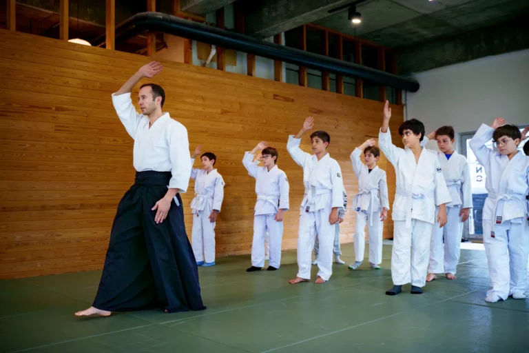 Hakamalı eğitmen kolunu kaldırıyor, çocuk aikido grubu sıra hâlinde hareketi tekrar ediyor, Katsu Ankara, Çayyolu.