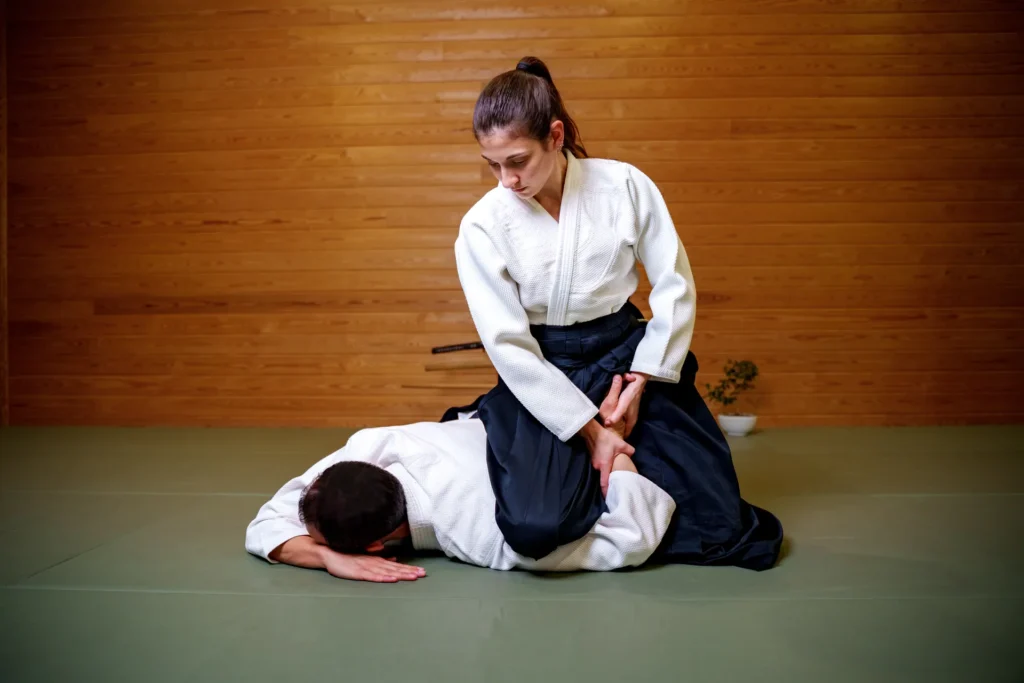 Kadın aikidoka erkek partnerini minderde kol kilidiyle sabitliyor, Katsu Ankara, Çayyolu.