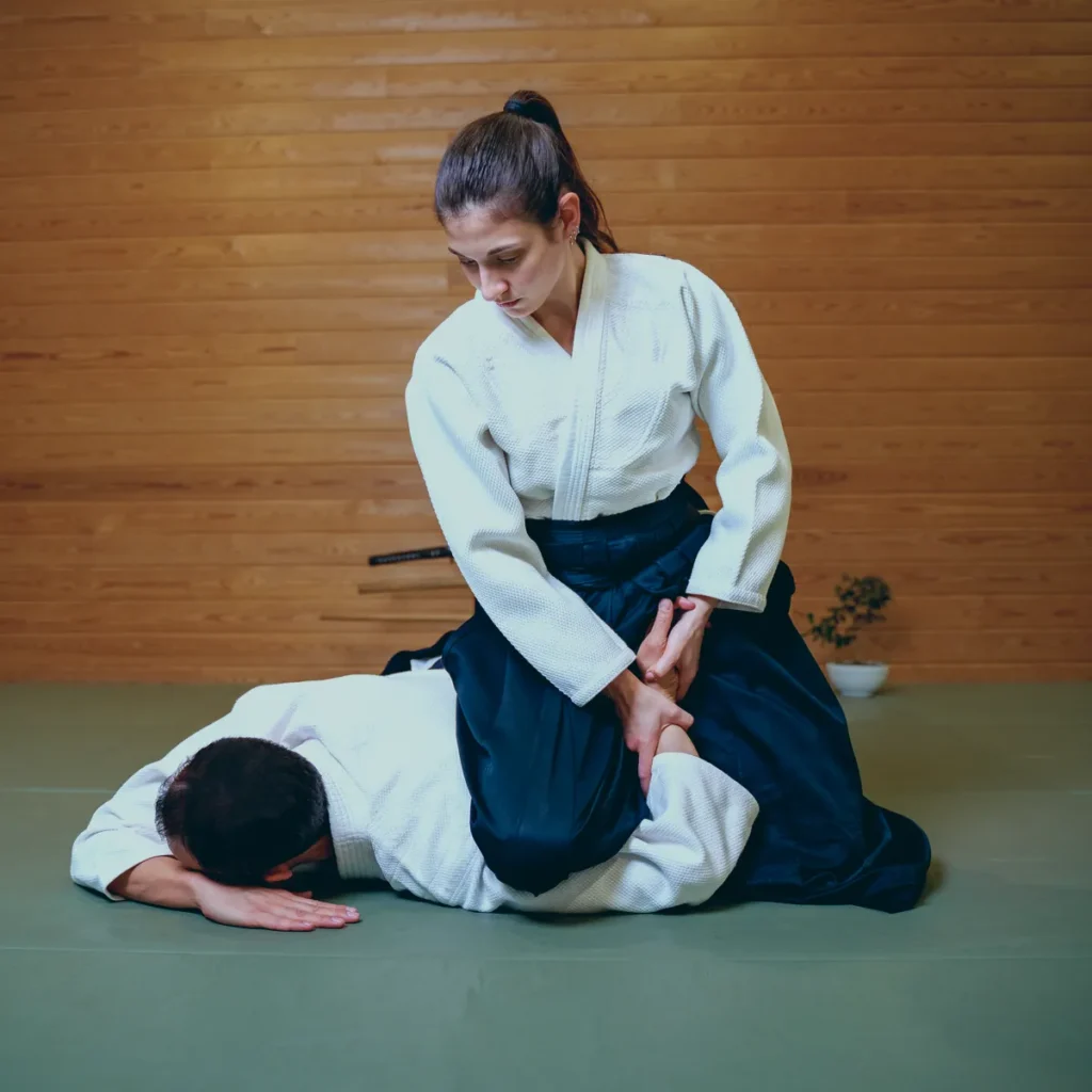 Hakamalı kadın aikidoka partnerini minderde kol kilidiyle sabitliyor, Katsu Ankara, Çayyolu.
